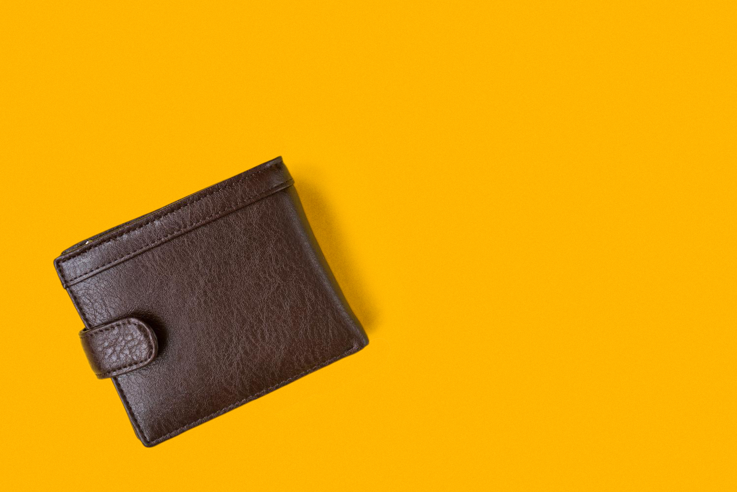 Lone brown wallet on a yellow background