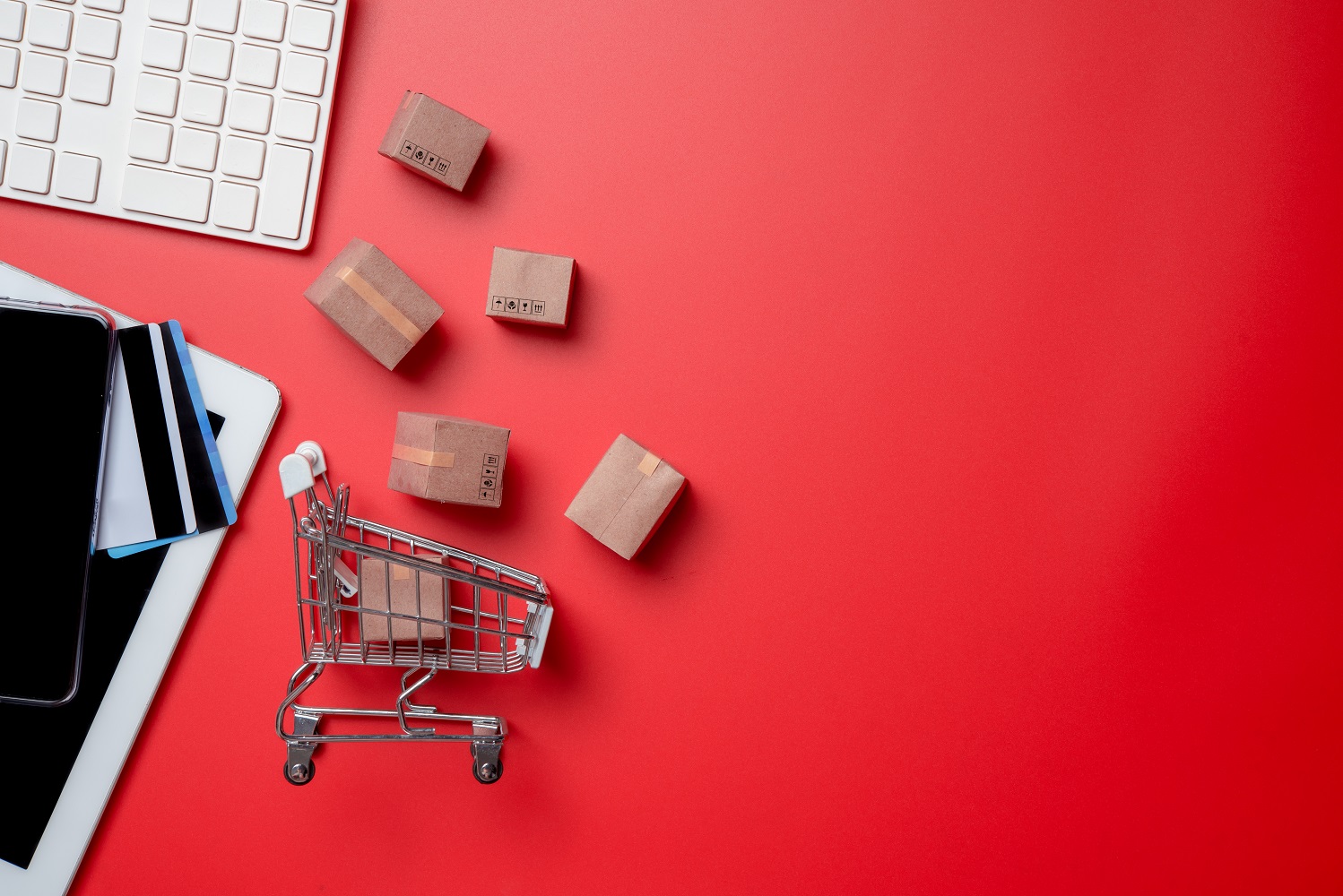 Online shopping, scatered office equpment and a miniature shopping cart