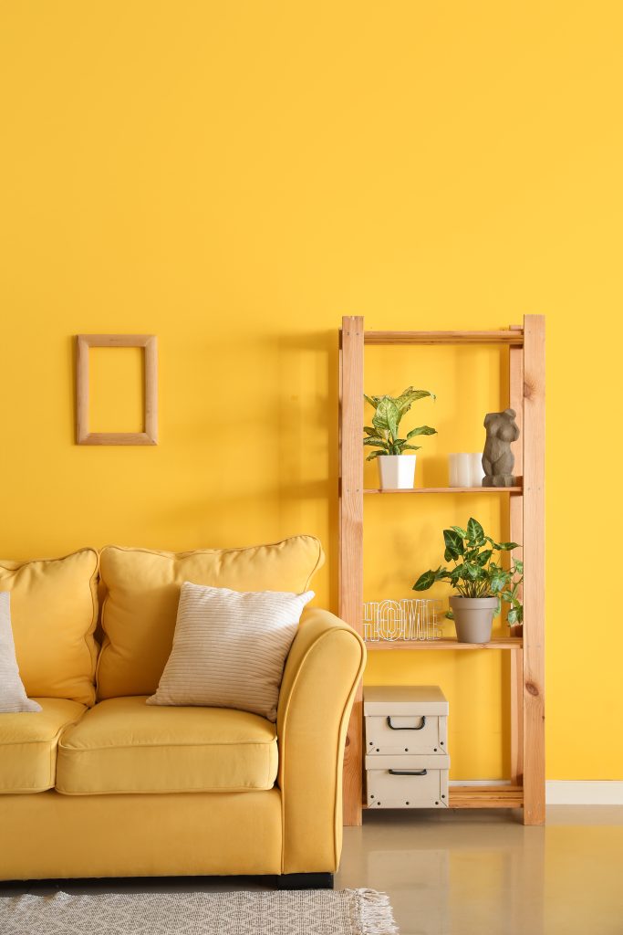 Interior of living room with yellow sofa and shelving unit